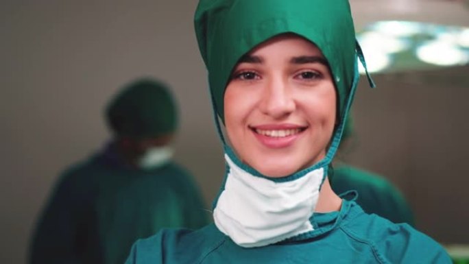 微笑的女医生的肖像对她的工作感到满意，并以医院手术室为背景。医学、技术、保健和人民、医院的概念