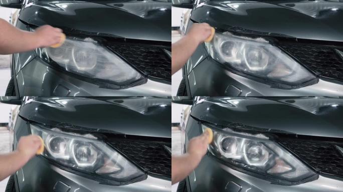 汽车细节。抛光机用海绵将特殊的抛光剂或糊剂或蜡涂在汽车前照灯的光学元件上，特写