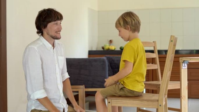 父亲和儿子用小零件组装木制家具。男人和男孩在完成椅子组装后互相给了五个。