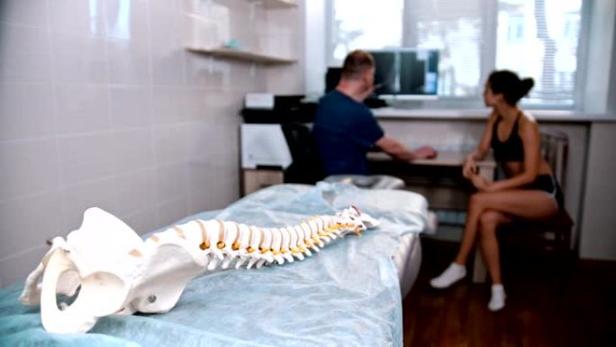脊椎治疗-医生在会议前检查年轻女子-人体脊柱模型