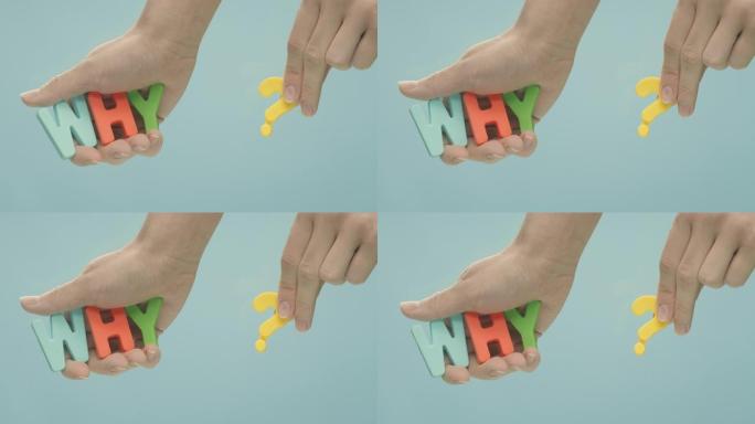 双手从水中拿出铭文 “为什么？”，这是由彩色塑料字母制成的。