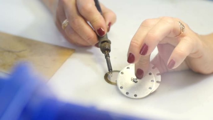 女人在工作场所用钎焊圆形金属穿孔细节