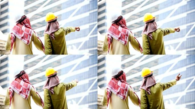 阿拉伯工程师共同咨询建筑项目的蓝图，指出了施工现场的严重问题现代穆斯林阿联酋城市。多元文化多样性商务