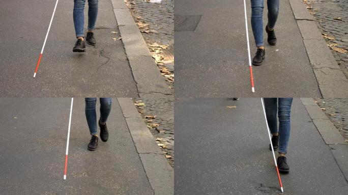 瞎了眼的年轻女子拄着拐杖走在街上。失明,取向