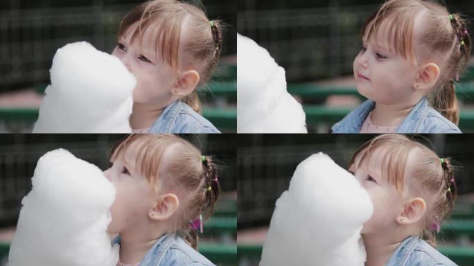 美丽快乐的小女孩在长凳上吃棉花糖