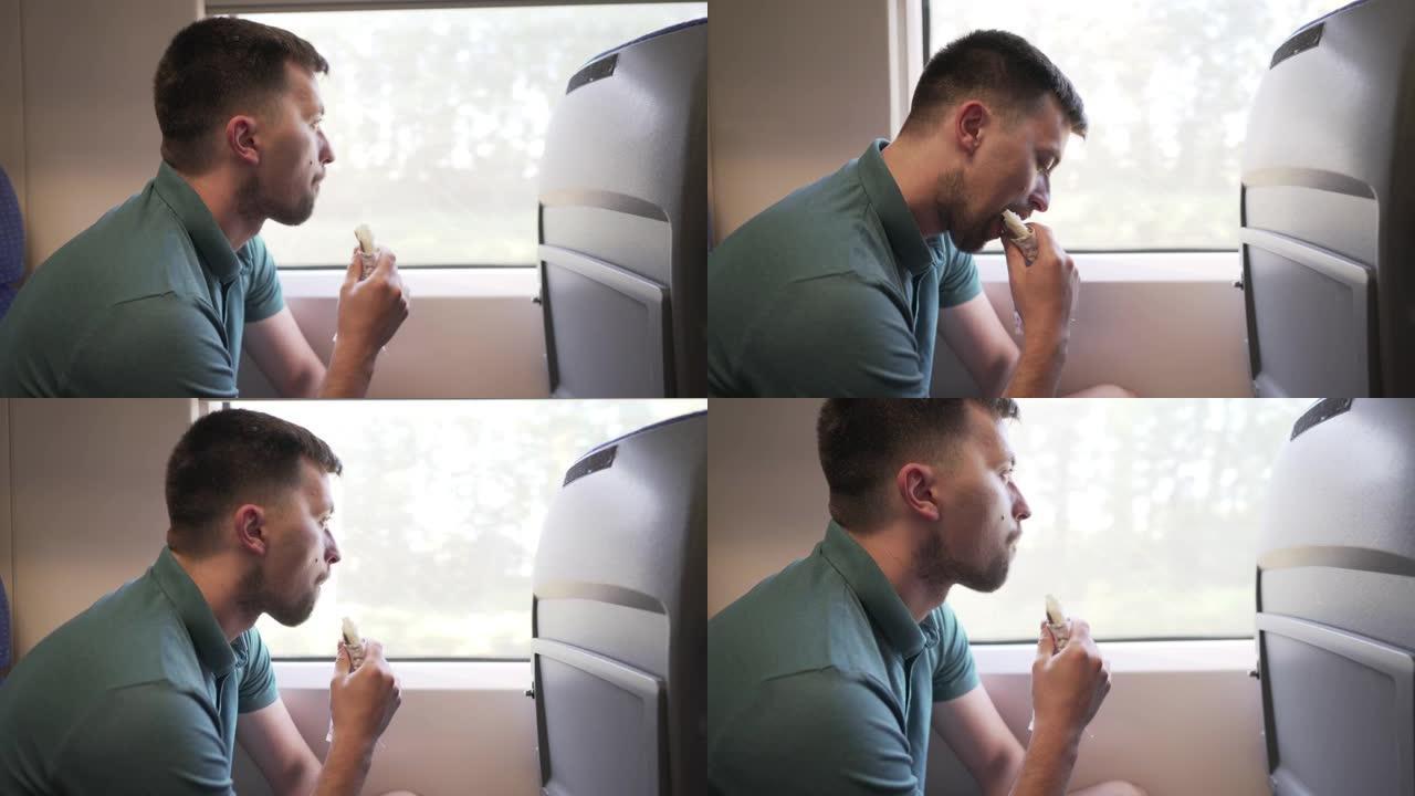 高加索男性旅行者乘坐旅客高速列车在靠窗座位上旅行，吃快餐三明治卷。铁路车厢内部。一个人独自坐火车旅行