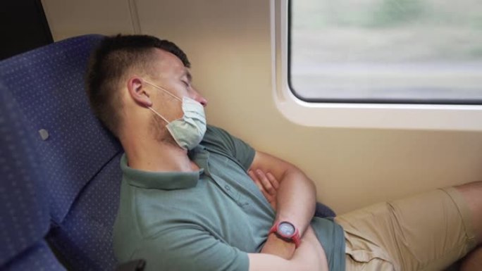 为了安全起见，疲倦的睡眠火车通勤者戴着PPE口罩。大流行期间的概念旅行。旅行期间的防护医用口罩。医用