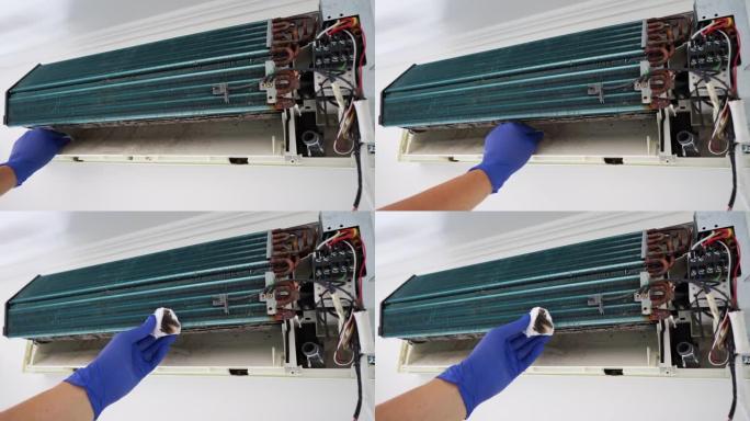 一名服务人员用棉絮擦拭拆卸的空调内的真菌
