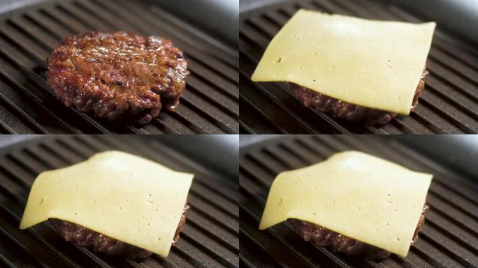 一块黄色奶酪落在烤盘上的油炸汉堡上。慢动作