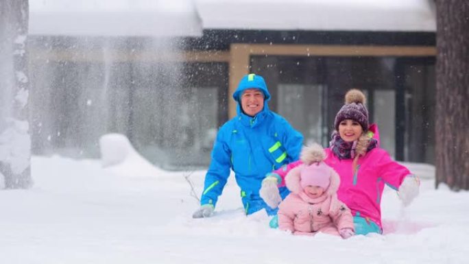 兴奋的家人坐在雪地里，笑着扔雪