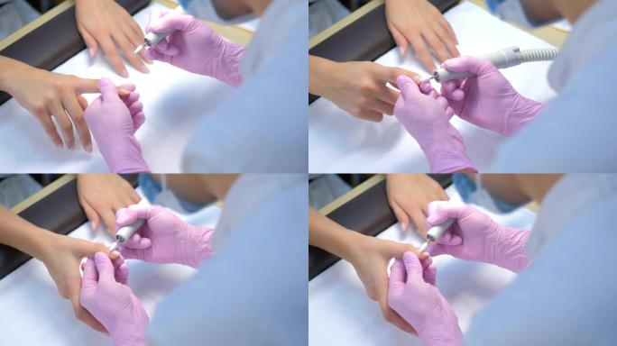 美甲师女人用修指甲机去除虫胶，双手特写。