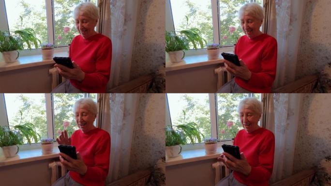 快乐的老年妇女拿着智能手机，在家使用社交媒体看手机屏幕，老年人和技术概念