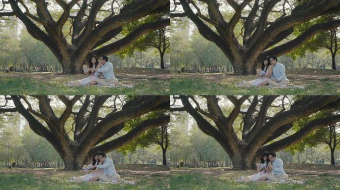 年轻夫妇骑在公园的一棵大树下接我，关于爱的日子的概念