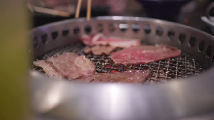 4k银通，筷子拿起新鲜的红色牛肉片放入烧烤架，日式餐厅，煤火，日式餐厅，午餐时间，火焰烤，主菜，肉类
