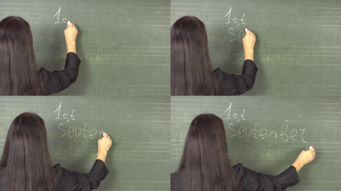 年轻的黑发老师用粉笔在9月1日上在黑板上写字。
