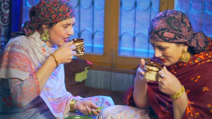 两个漂亮的喜马偕理女人闲聊，在家里剥豌豆和喝茶。