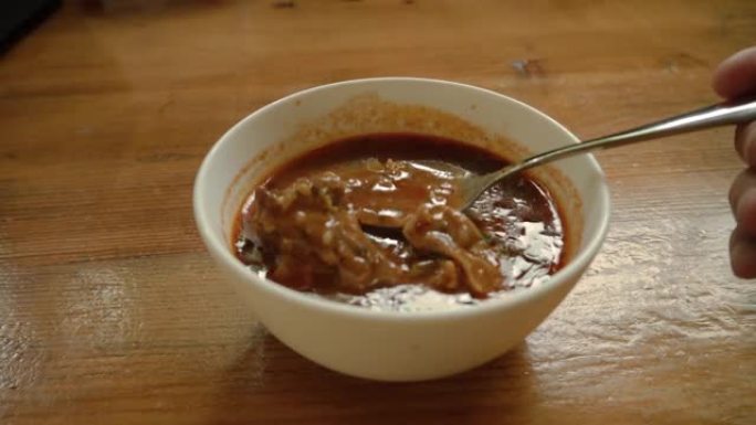 餐厅里一碗热腾腾的格鲁吉亚kharcho汤配肉。男人用勺子搅动汤里的羊肉块。