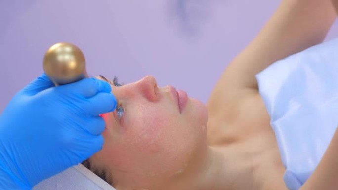 美容师医生在女人脸上做语音电泳手术，侧视图。