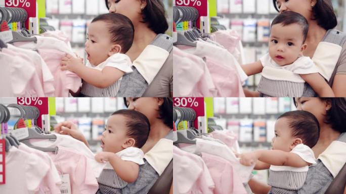 一个亚洲男婴和他的母亲在一家儿童服装店抱着。