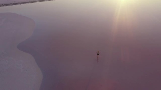 在粉红色盐湖上行走的妇女的风景鸟瞰图