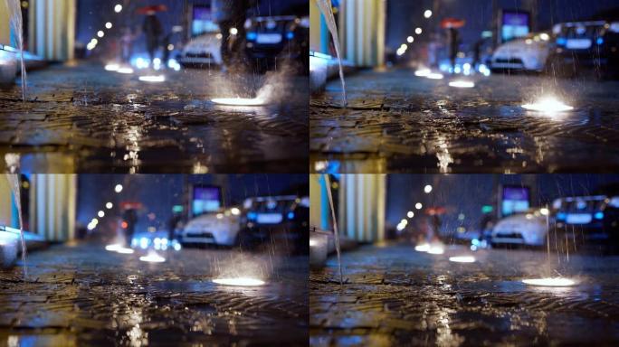 夜间，城市街道上的雨水以慢动作落下，地面灯光