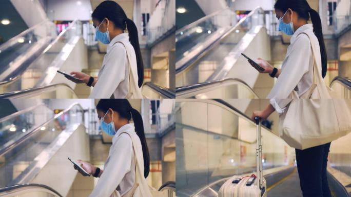 女商人戴着口罩面部保护，站在机场航站楼的自动扶梯上使用智能手机，并在新型冠状病毒肺炎大流行期间保持社