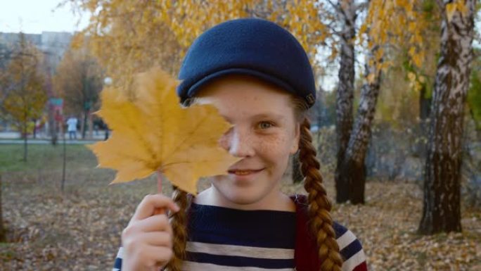快乐的女孩在公园里抱着树叶，眯着眼睛