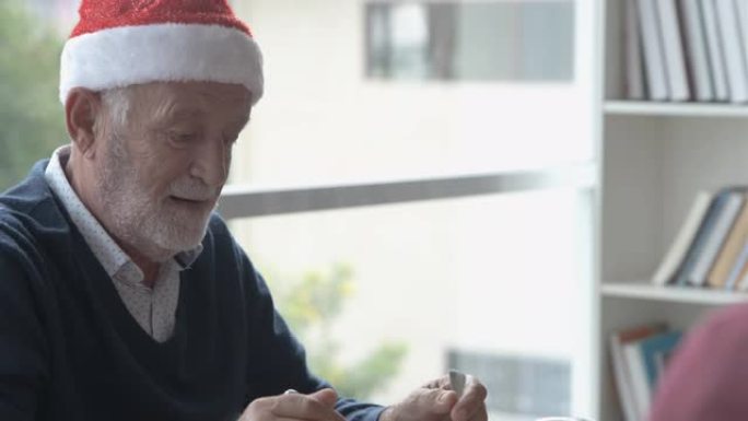 戴红帽子的老人在圣诞节用餐时与家人讨论