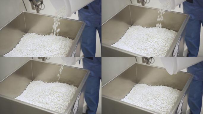 制药厂的药剂师从桶里倒出药丸。一堆白色药片