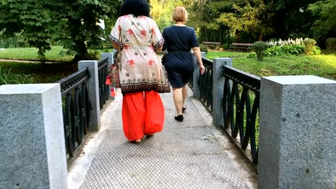 两个成熟的成年女性在公园散步。在阳光明媚的夏日。