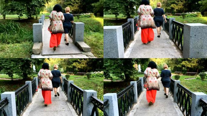 两个成熟的成年女性在公园散步。在阳光明媚的夏日。