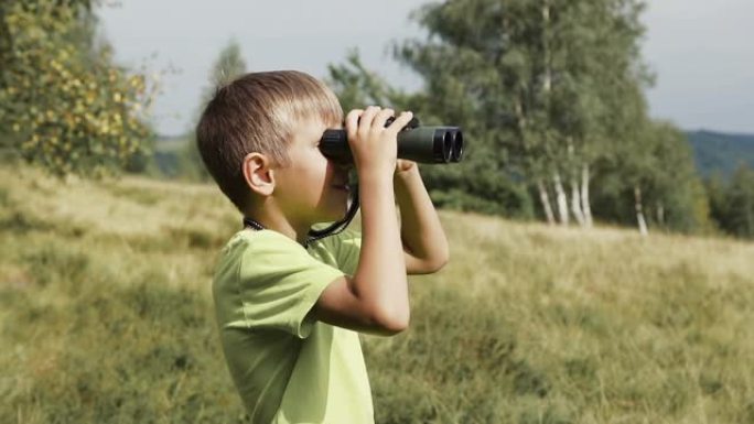 男孩站在山顶上，看着双筒望远镜