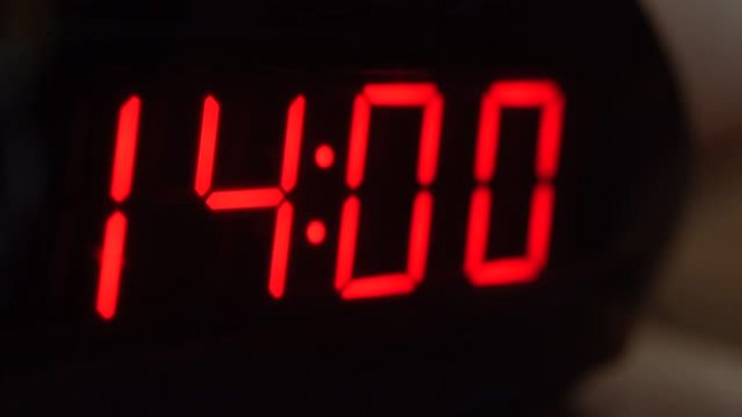 黑色数字时钟屏幕的特写显示14.00。黑色背景上闪烁红色数字。现代定时器系统和霓虹灯、电动报警装置