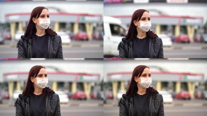 戴着医用面具的年轻女子望着远处，站在城市的街道上。女性在行走中保护自己免受疾病侵害的特写镜头。冠状病