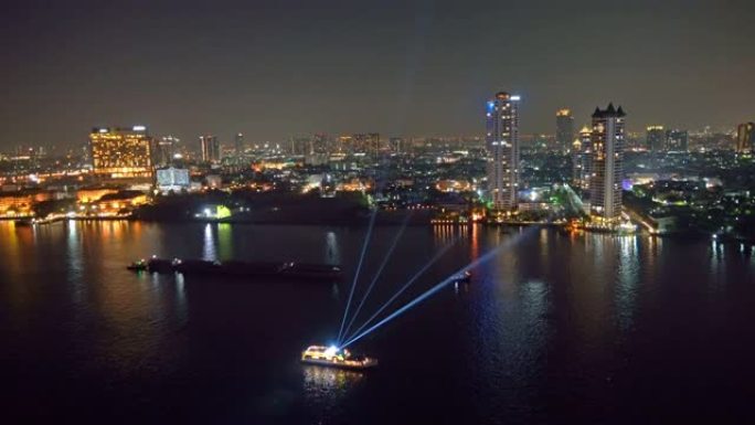 泰国曼谷市中心的湄南河 (Chao Phraya) 上有船或游轮的彩色激光表演。亚洲智慧城市的金融区