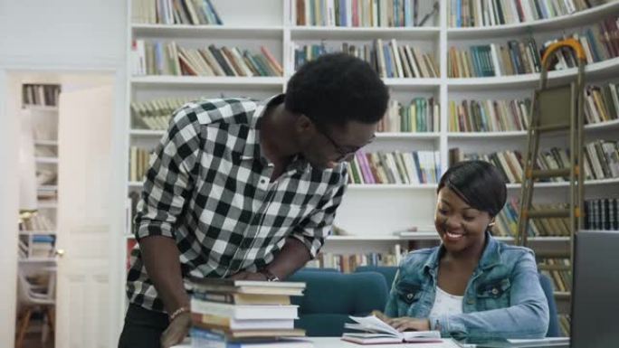多莉拍摄的非洲男学生穿过图书馆，给五个有吸引力的非洲女学生，并开始在图书馆一起学习