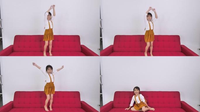 快乐的亚洲儿童女孩在家里的沙发上跳跃。