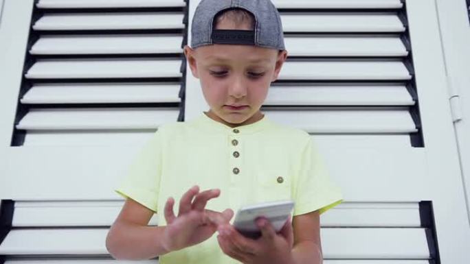 年轻的少年在智能手机上玩游戏，孤立在白门背景上。玩智能手机技术的孩子。在智能手机上写信息的小男孩的特