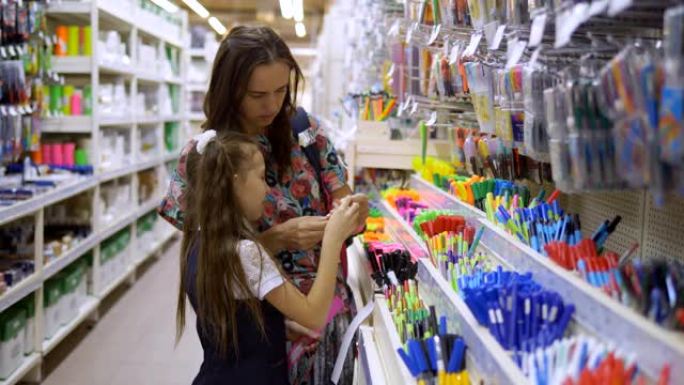 一家文具店的母女俩选择学习用品。超市里的家庭选择文具写字笔。