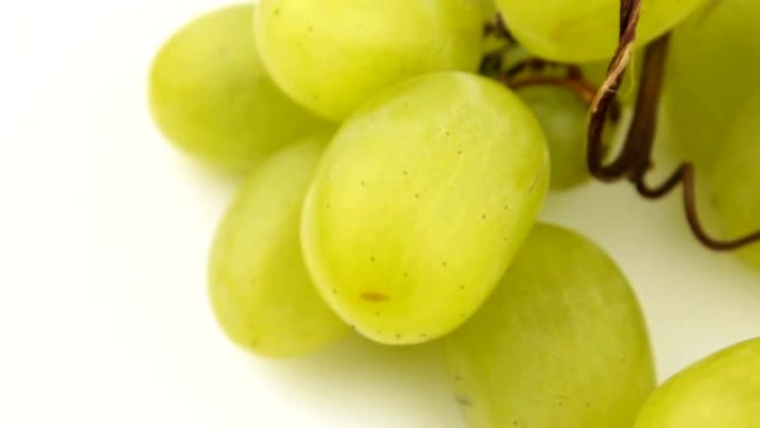 新鲜一束多汁的葡萄在白色背景上旋转。成熟多汁的葡萄在盘子上旋转。一串白葡萄的特写。