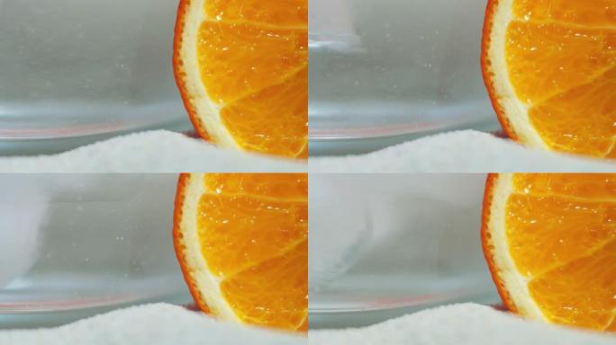 橙色背景上的沙子上有冰和苏打水的透明玻璃