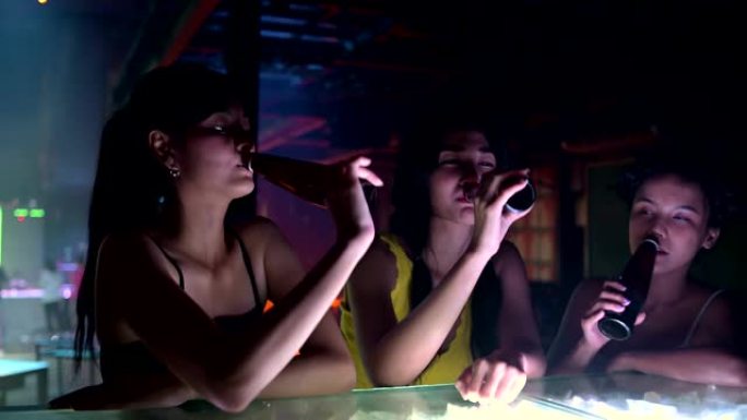 年轻的亚洲妇女在nig喝酒并与朋友聊天