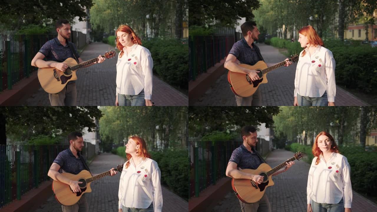 年轻音乐家的二重唱。男人弹吉他。女人在唱歌。日落夏夜的城市公园
