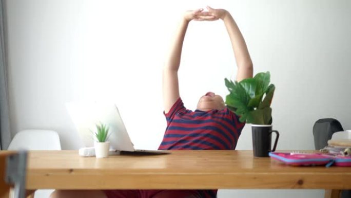 亚洲男孩在新型冠状病毒肺炎期间使用笔记本电脑在家上学后加强手臂。