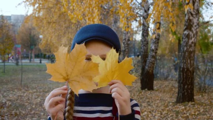 可爱的孩子在秋天的公园里玩黄叶