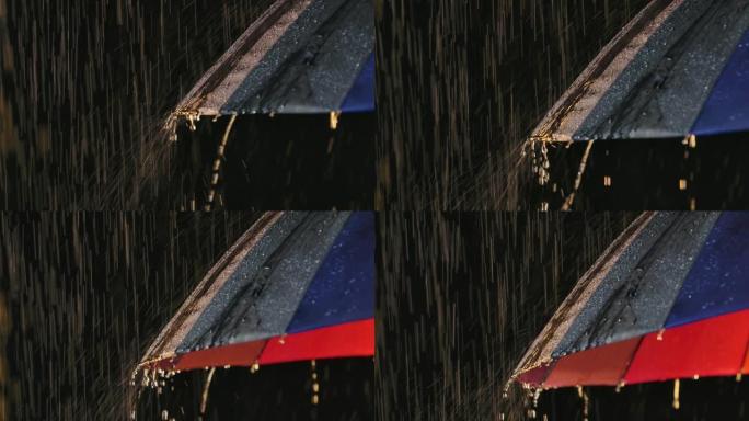 雨水从潮湿的雨伞中流下。水滴在黑色背景下的演播室灯光中闪闪发光。以慢动作拍摄特写镜头