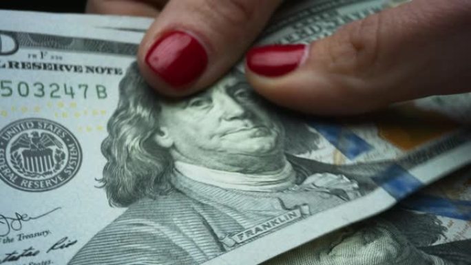 女人数着手享受美元钞票。领取工资的女士