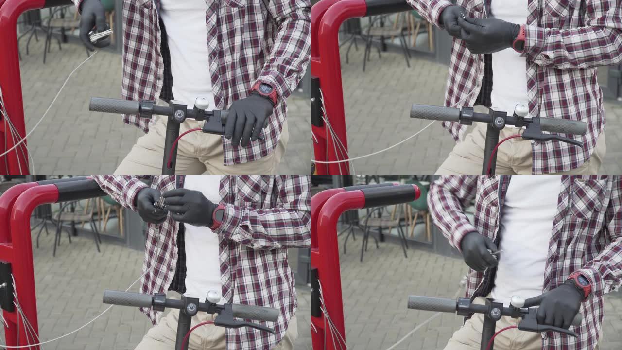 年轻人在维修站用工具修理戴着黑色橡胶手套的电动推动踏板车。电动汽车修理工在商店附近的车间工作。现代环