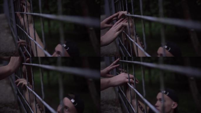 男孩和女孩用手指通过铁笼互相触摸。