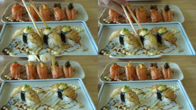 手吃aburi engawa nigiri或比目鱼鳍烧寿司，搭配酱汁和蛋黄酱日本食物